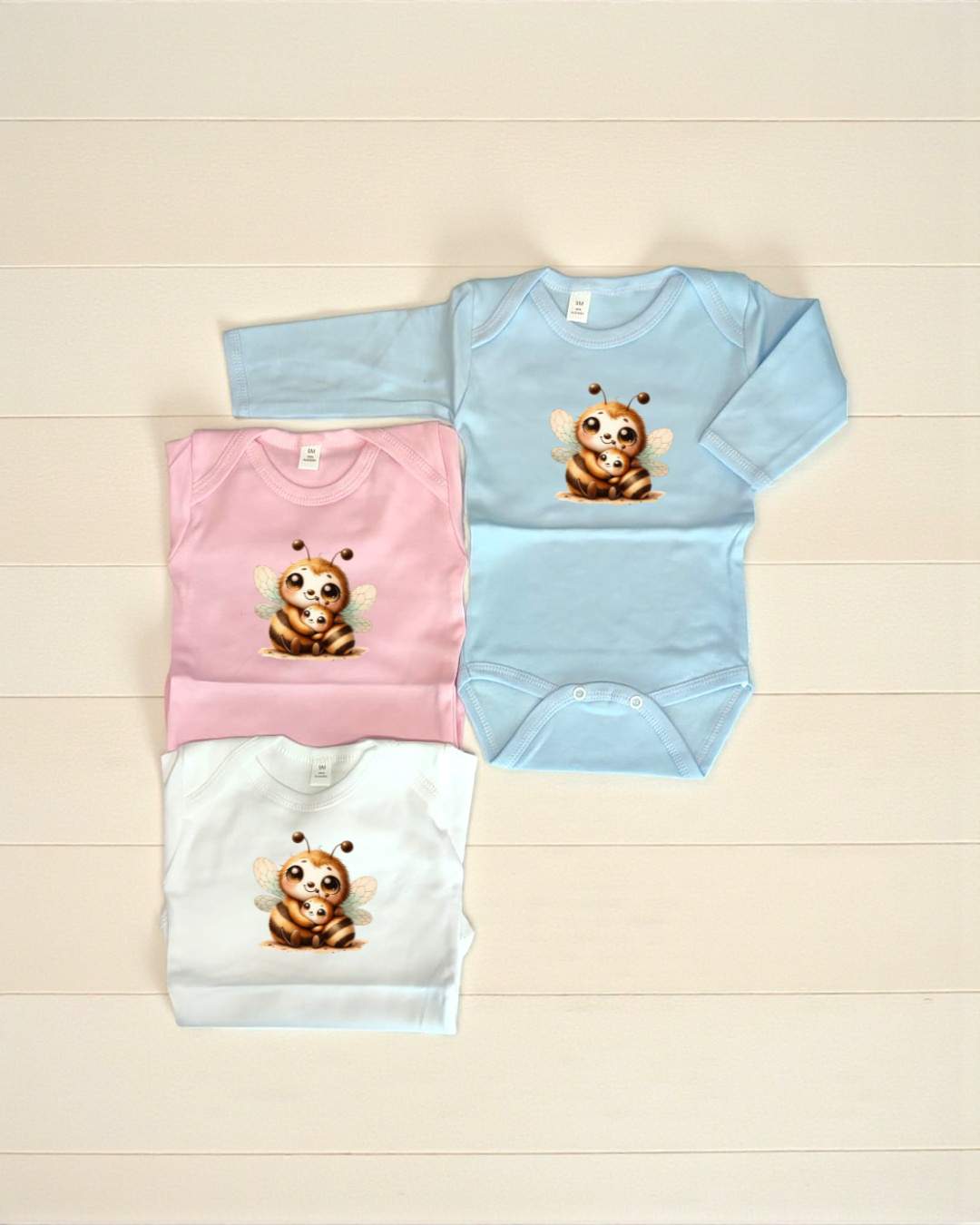 Bodies de bebé azul claro, rosa e branco com estampa de mãe abelha e cria.