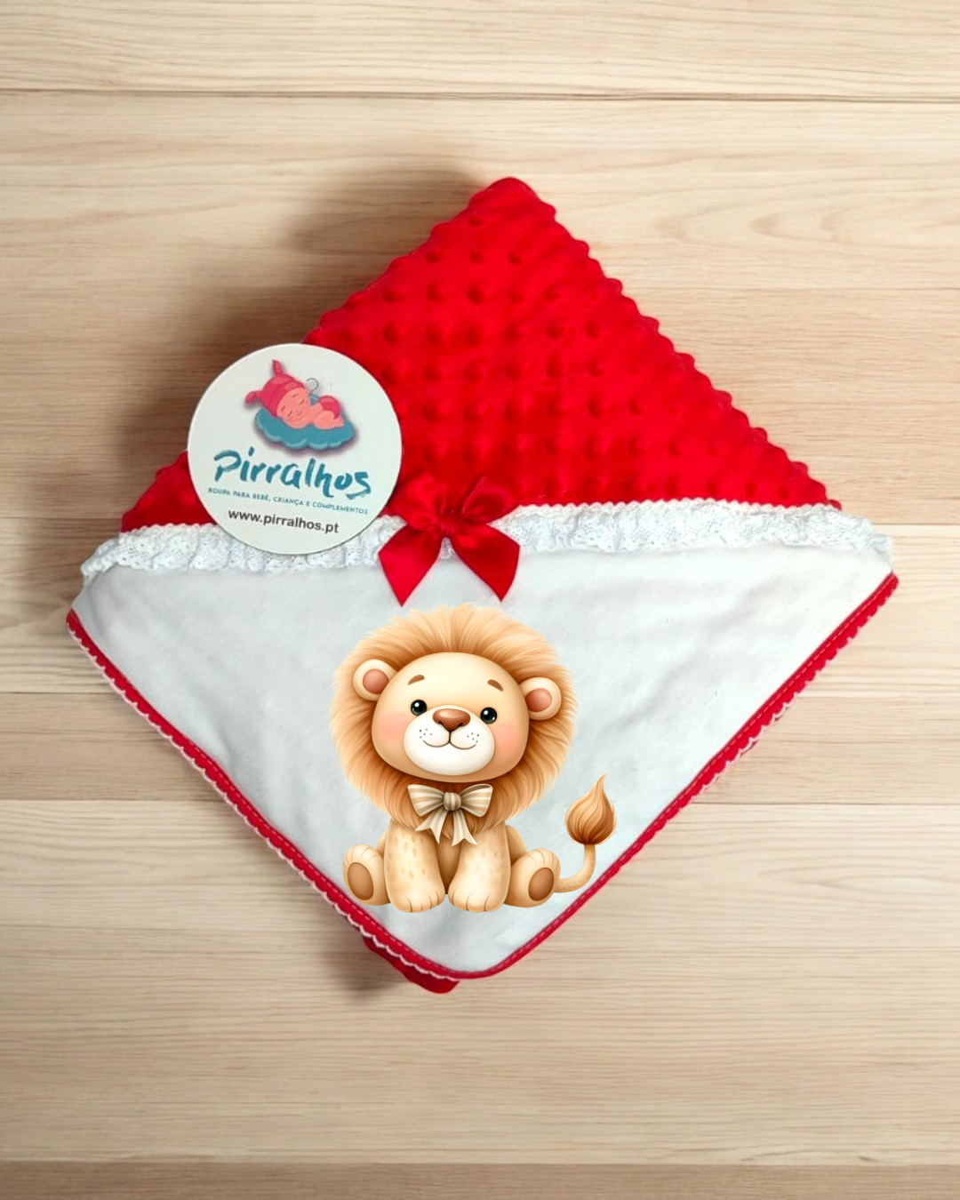 Manta bebé vermelha e branca com textura e laço, etiqueta Pirralhos, sobre madeira