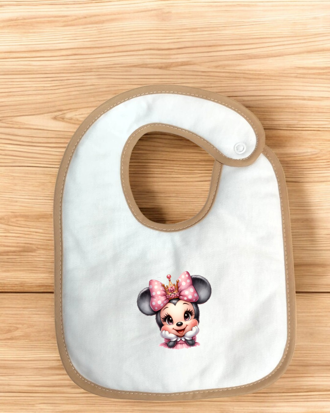 Babete branco com bordas bege e estampa infantil colorida colocado sobre madeira clara