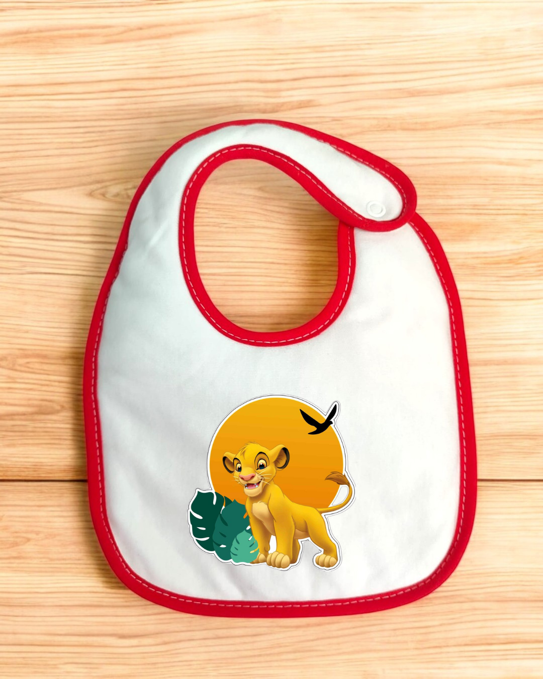 Babete branco com bordas vermelhas e imagem de Simba no centro