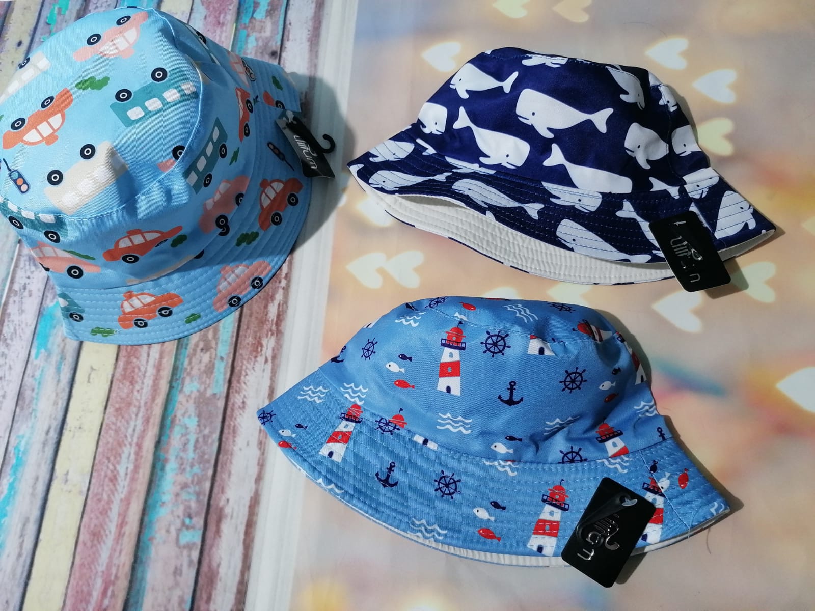 Três chapéus infantis estampados em tecido azul claro e azul escuro sobre fundo colorido