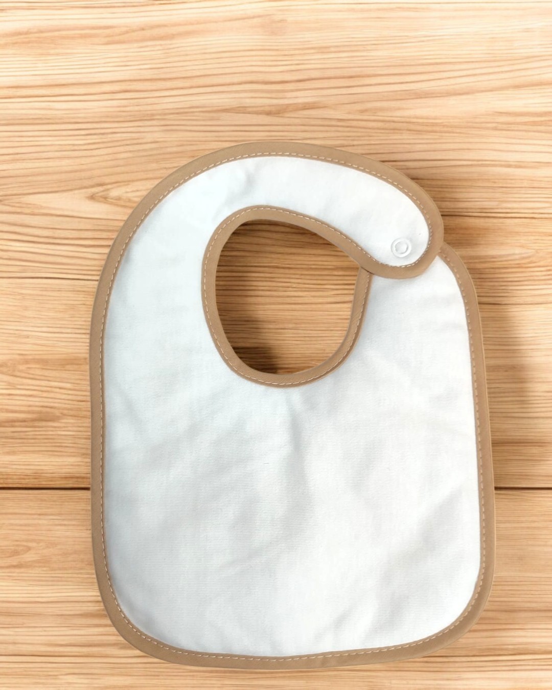 Babete branco com bordas bege sobre superfície de madeira clara