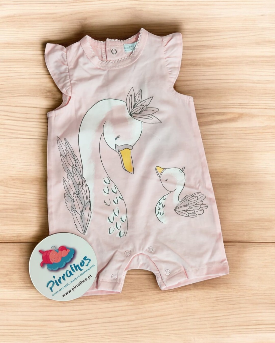 Body de bebé cor-de-rosa com desenho de cisnes e etiqueta redonda ao lado