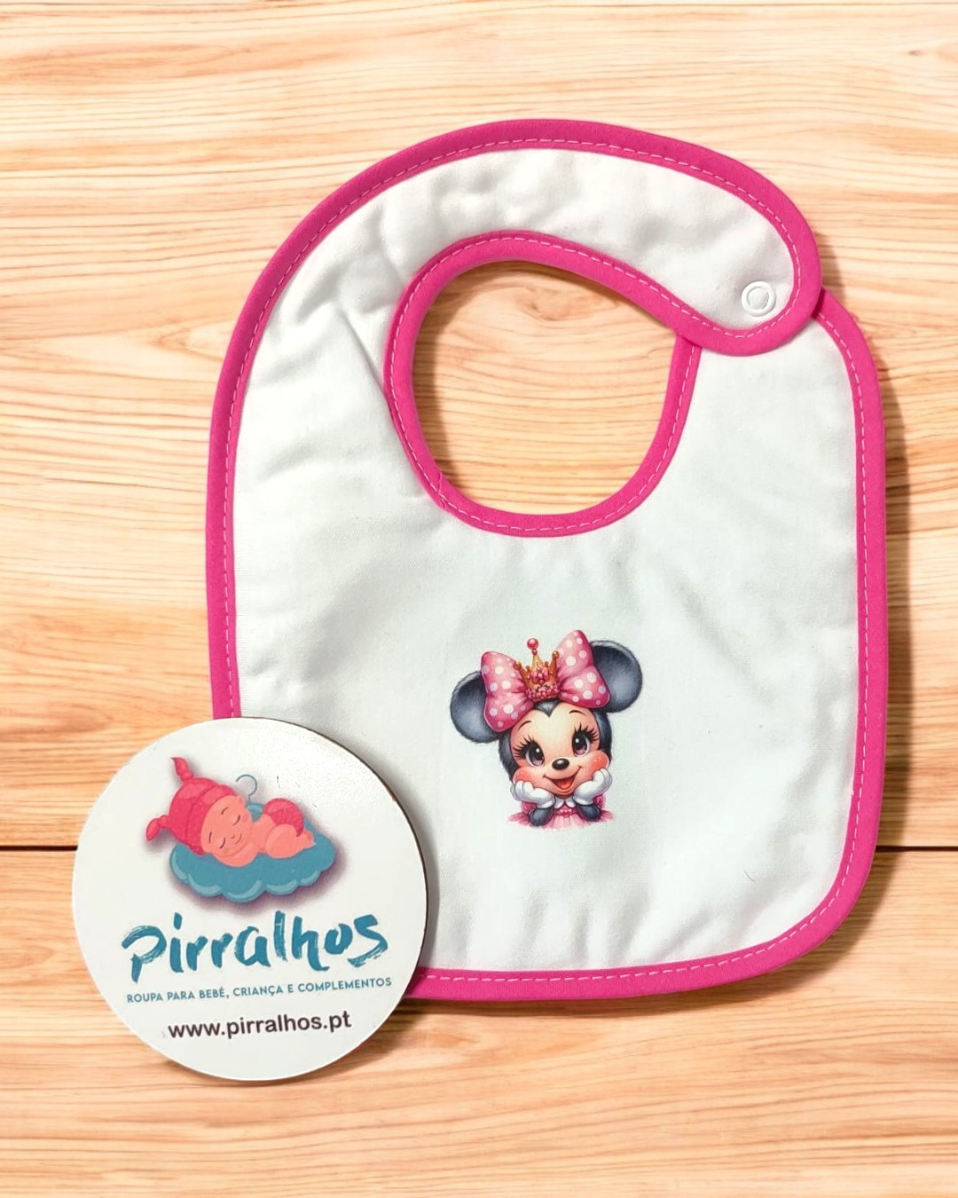 Babete branco com bordas cor-de-rosa e figura infantil com laço rosa no centro