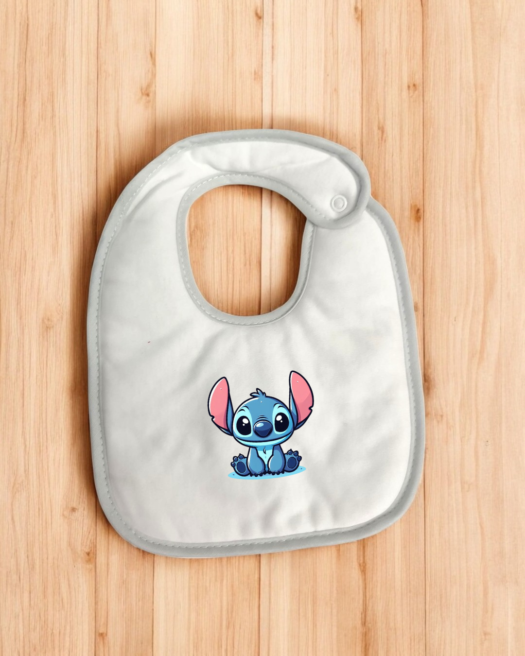 Babete branco com imagem do Stitch em fundo de madeira clara