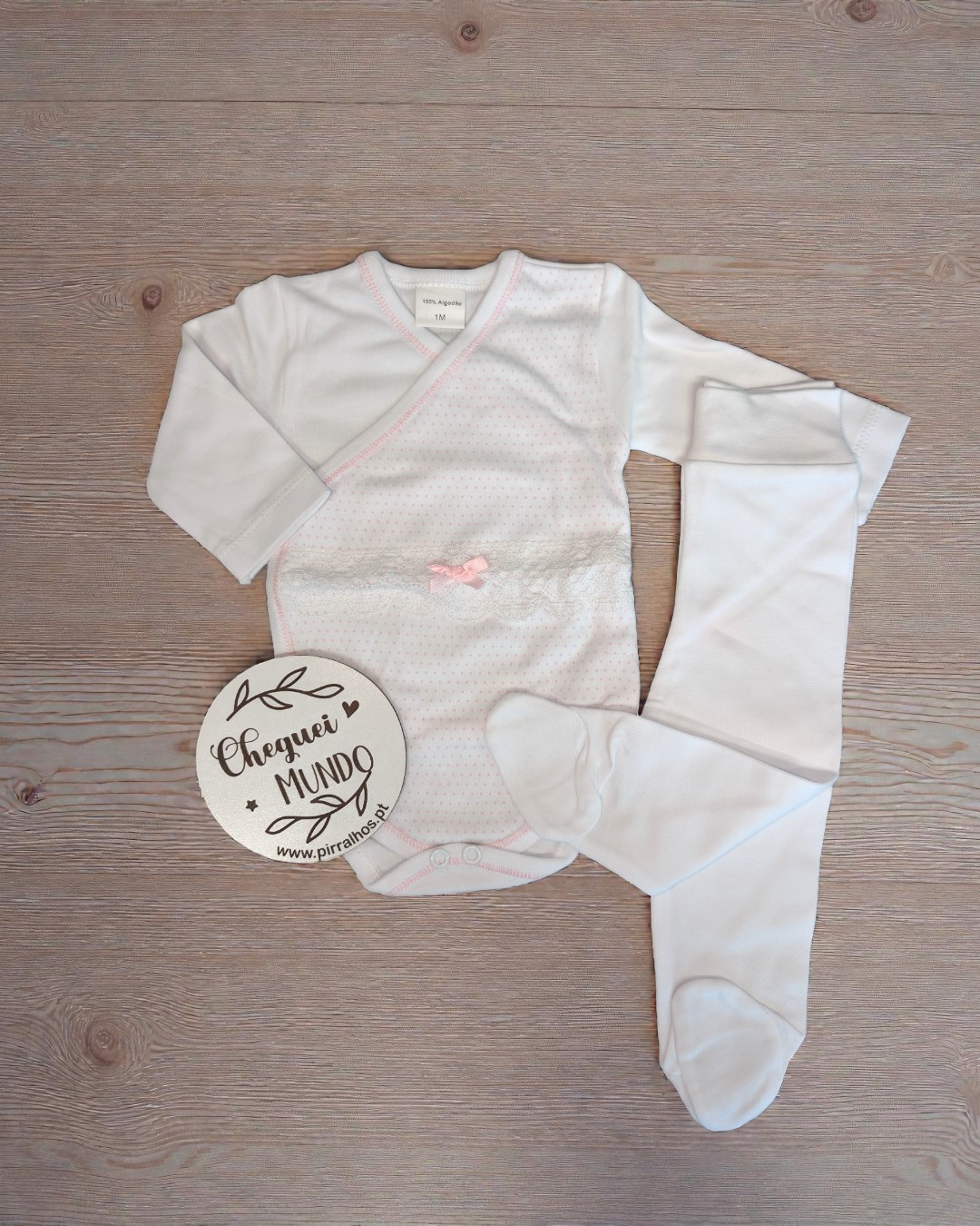 Conjunto de roupa de bebé branco com body e meia-calça sobre madeira clara