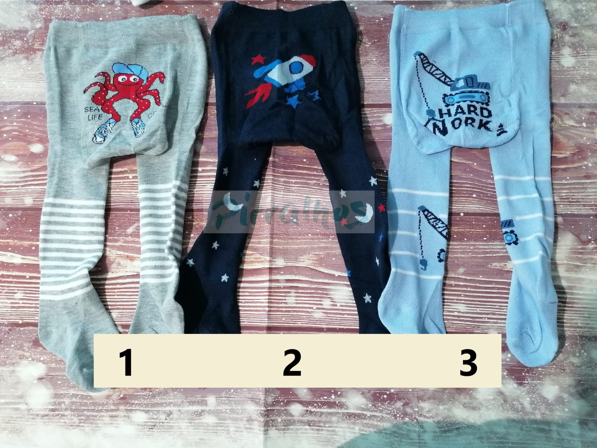 Três pares de collants infantis com desenhos de caranguejo, foguete e machado com texto HARD WORK