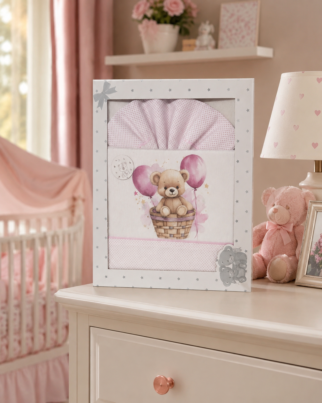 Caixa com jogo de cama para bebé com desenho de ursinho e balões cor-de-rosa.
