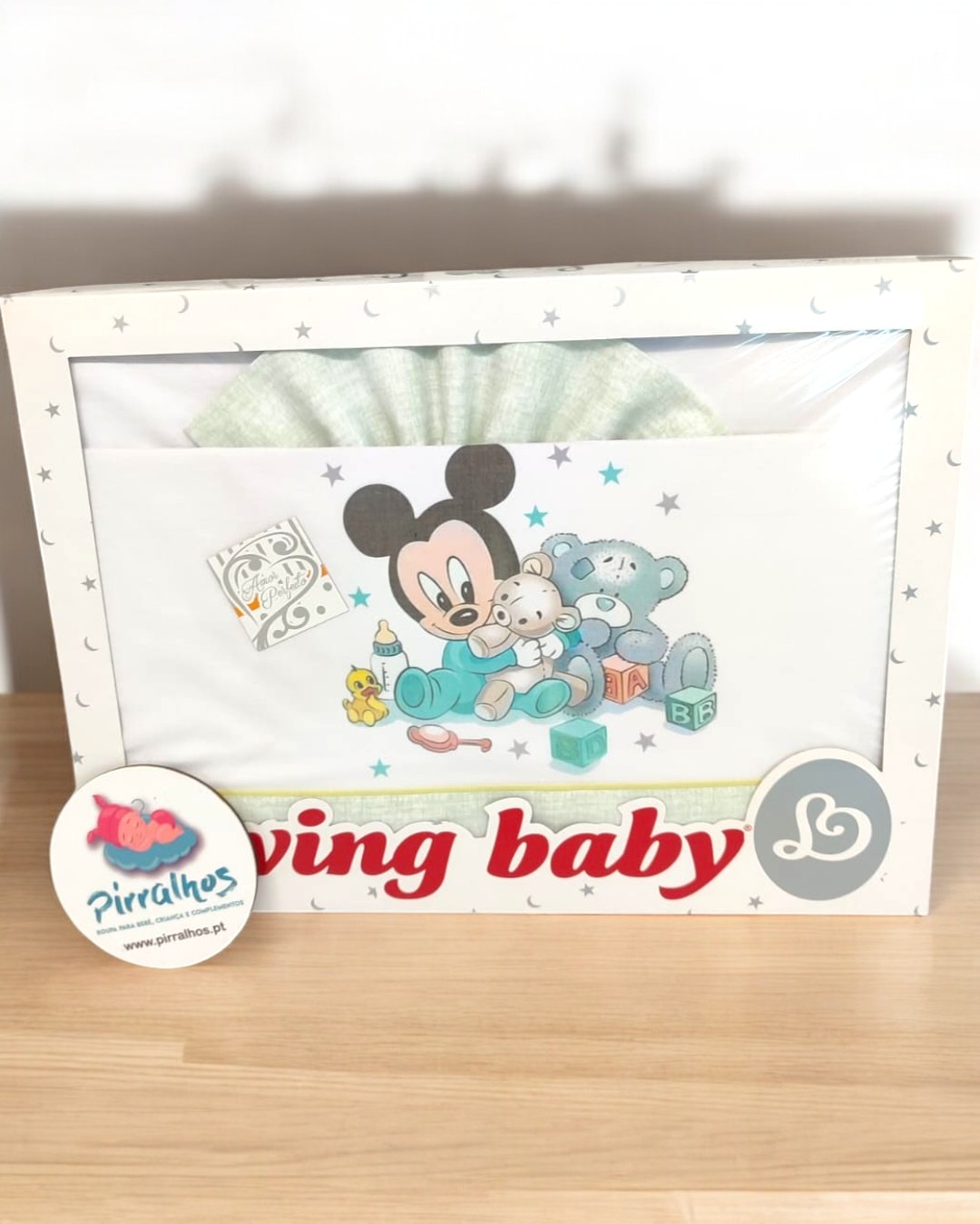 Fralda de bebé com desenho do Mickey Mouse e ursinho embalada numa caixa branca com estrelas.