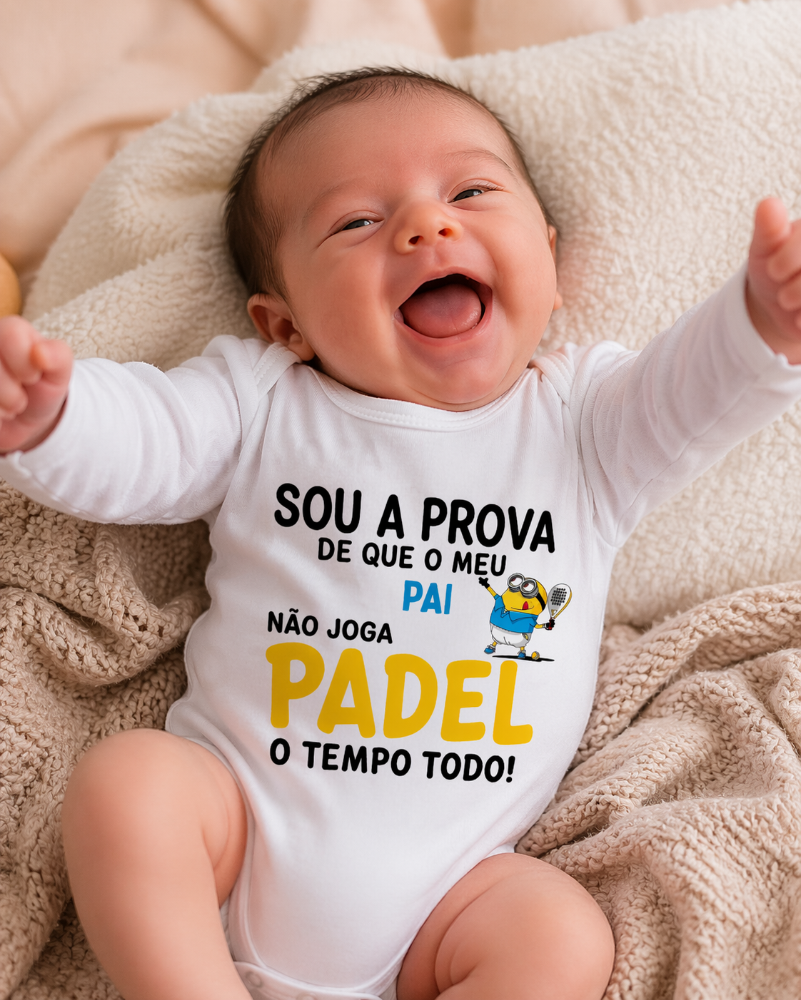 Bebé sorridente deitado com body branco com texto e ilustração de Minion a jogar padel