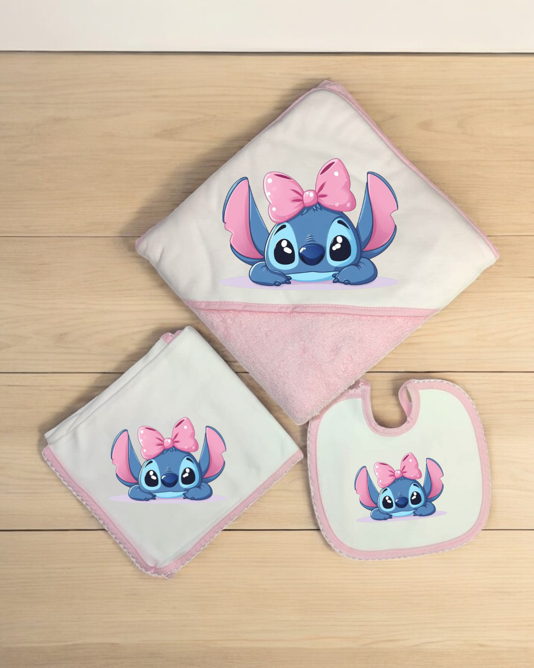 Conjunto de banho para bebé com personagem azul e laço rosa em fundo branco e rosa