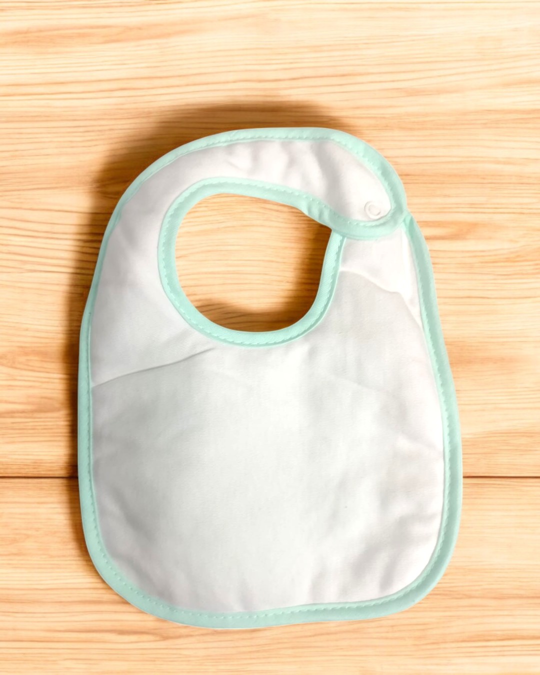 Babete branco com borda azul clara sobre superfície de madeira