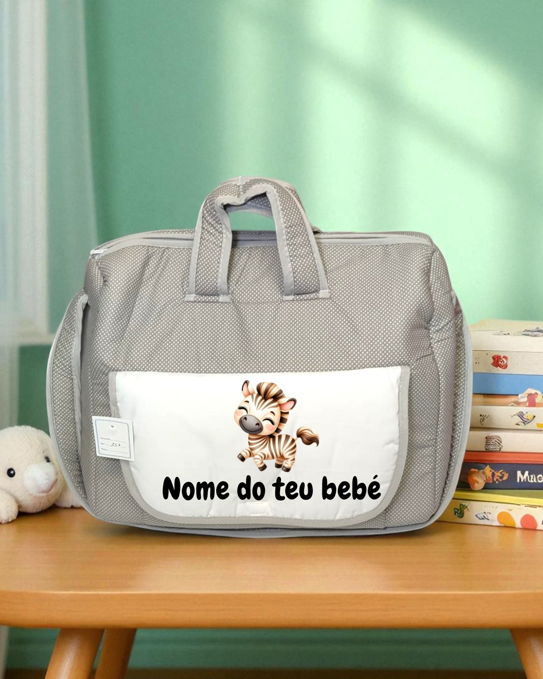 Mala de bebé cinzenta com bolso branco e desenho de zebra na mesa de madeira
