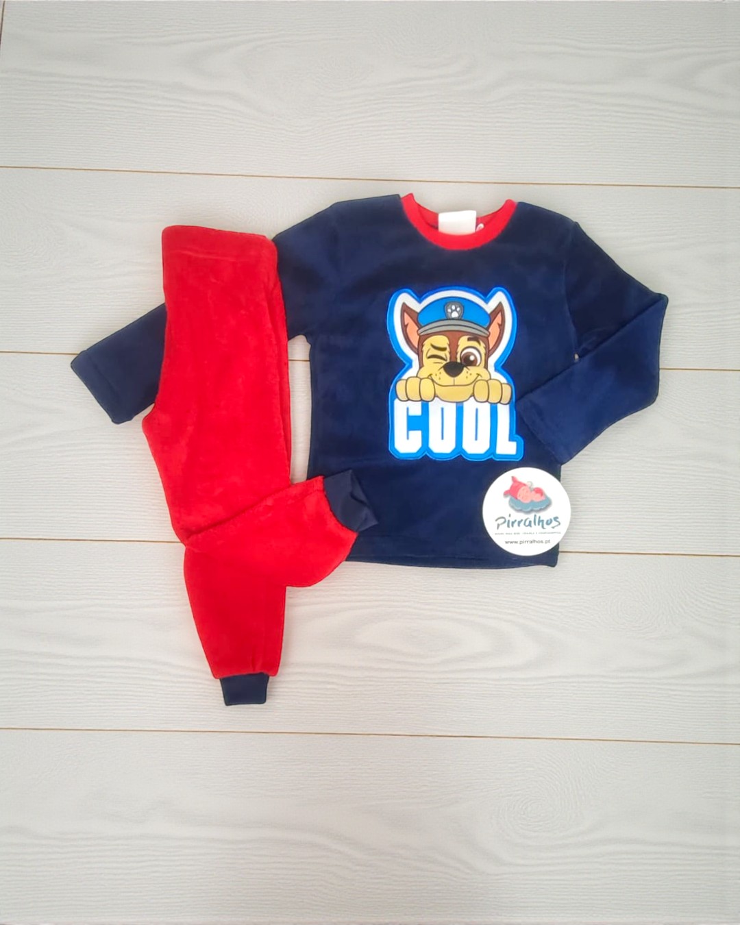 Conjunto de roupa para criança com camisola azul e calças vermelhas em fundo claro