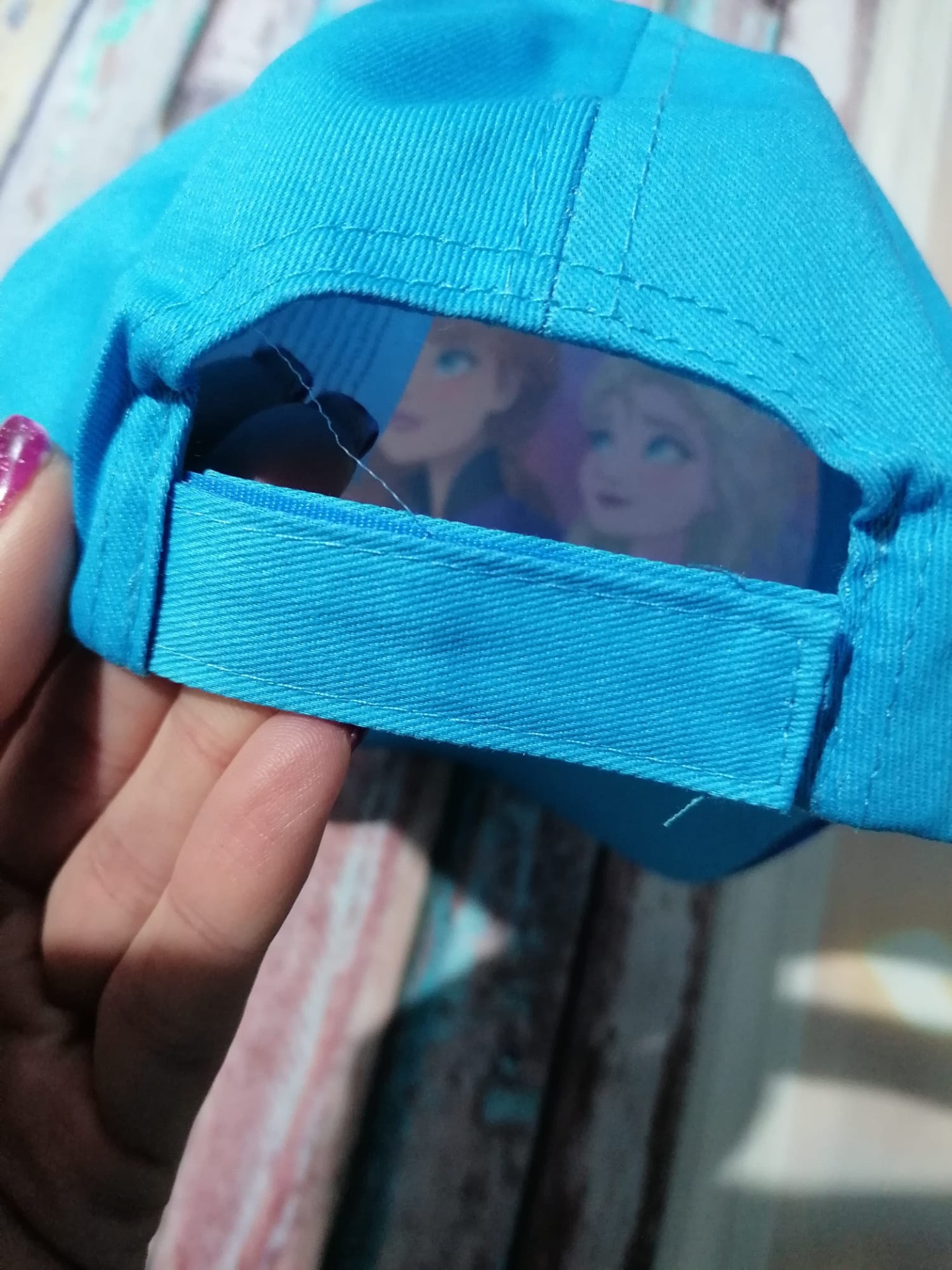 Boné azul claro com ajuste traseiro de velcro e imagem colorida de personagens femininas