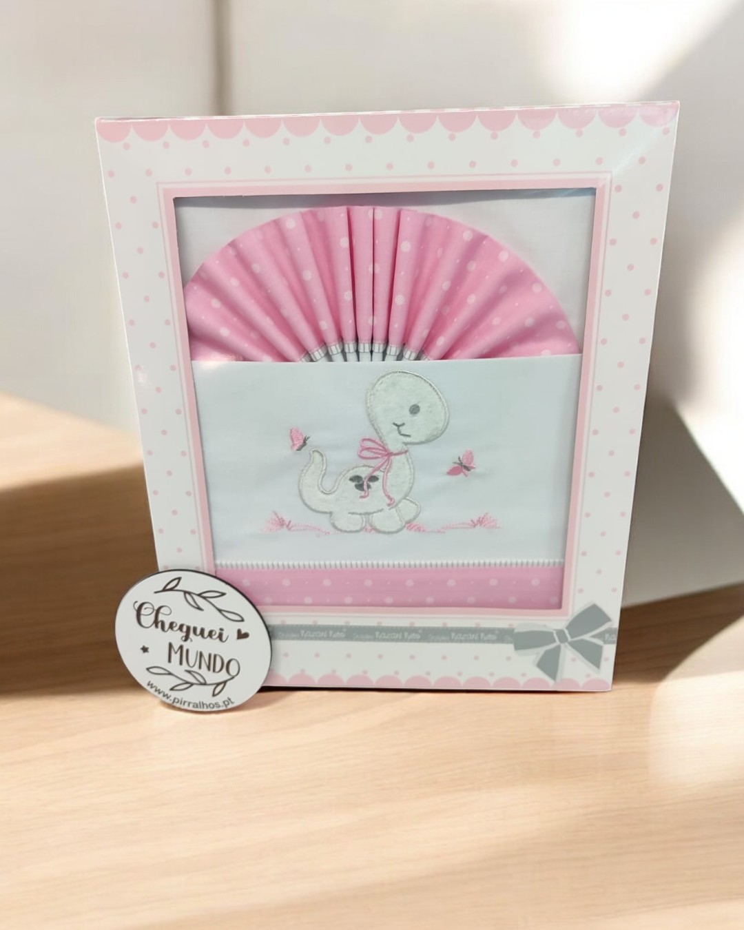 Fralda branca bordada com dinossauro e lenço rosa em caixa decorada