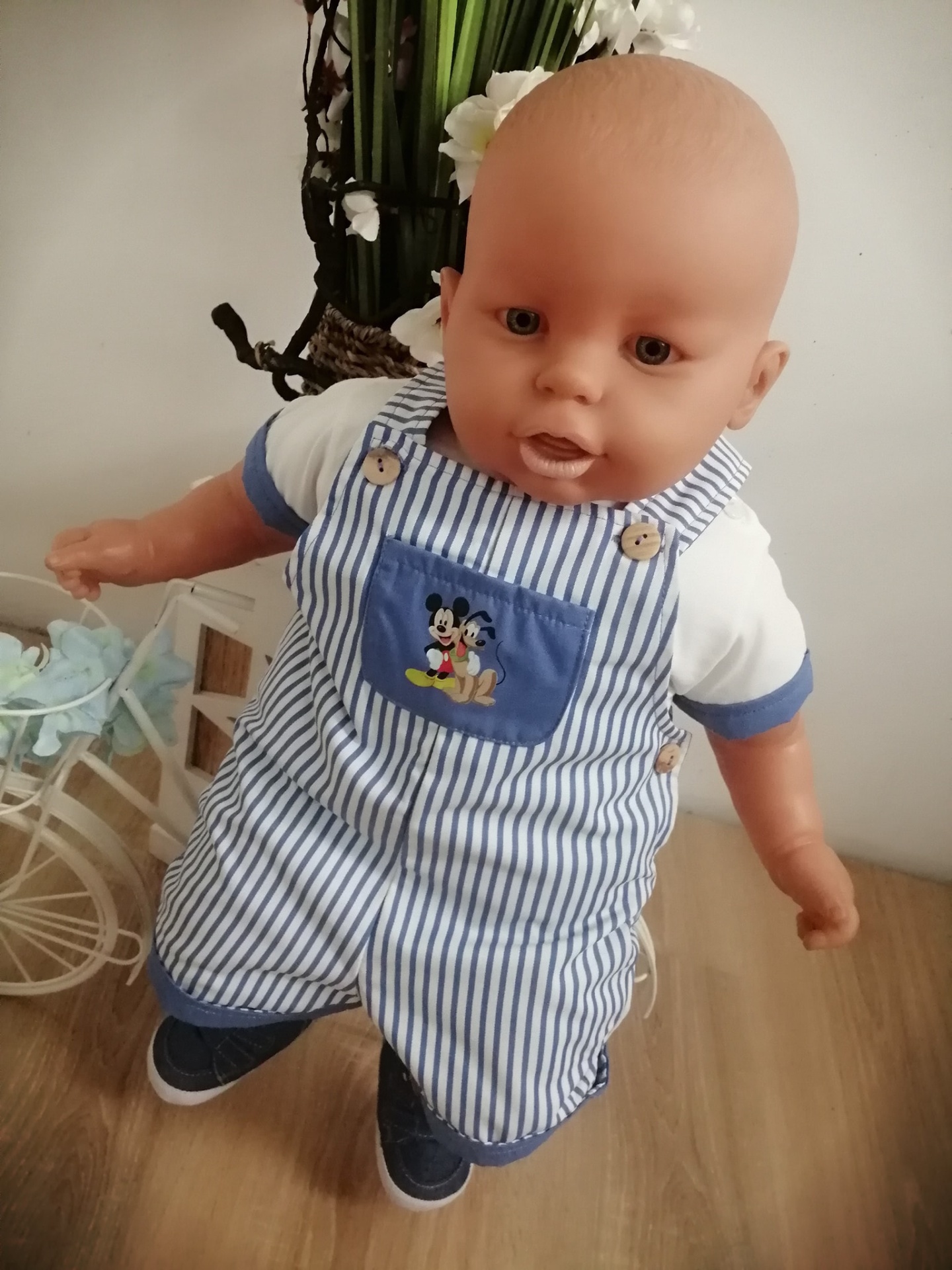 Boneco de bebé com macacão azul e branco às riscas e t-shirt branca