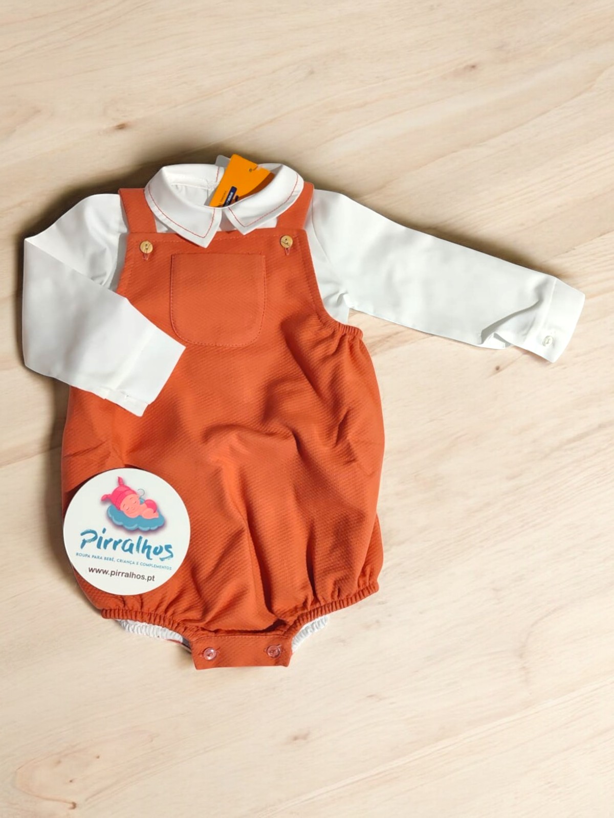 Conjunto de bebé branco e laranja sobre madeira clara