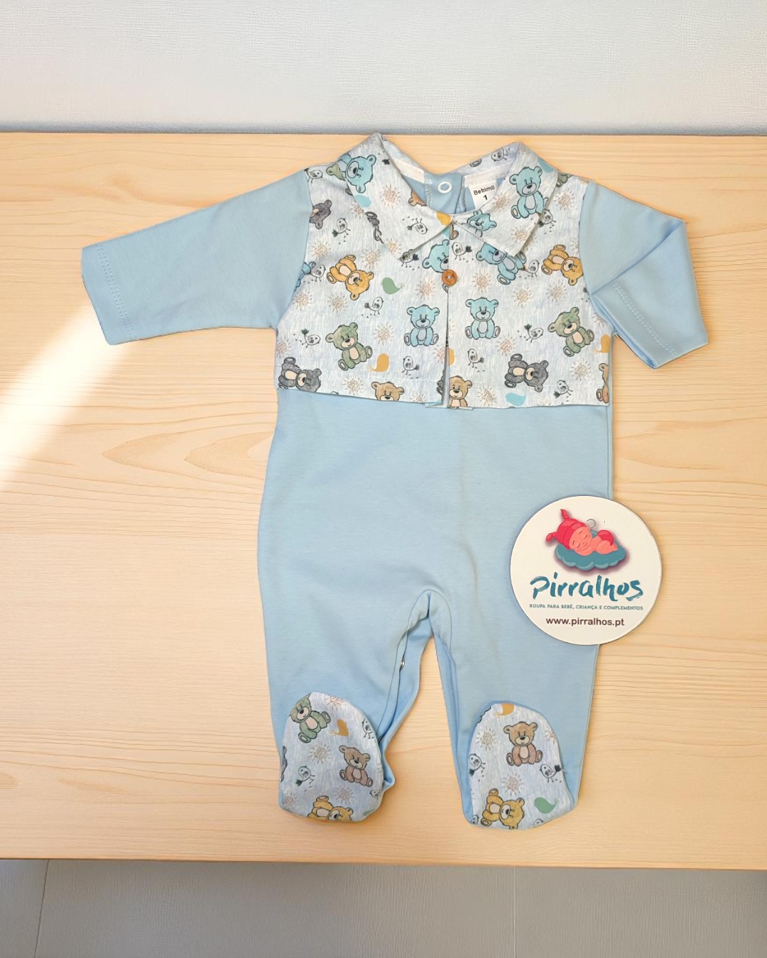 Macacão azul claro para bebé com padrão de ursinhos e etiqueta da marca Pirralhos
