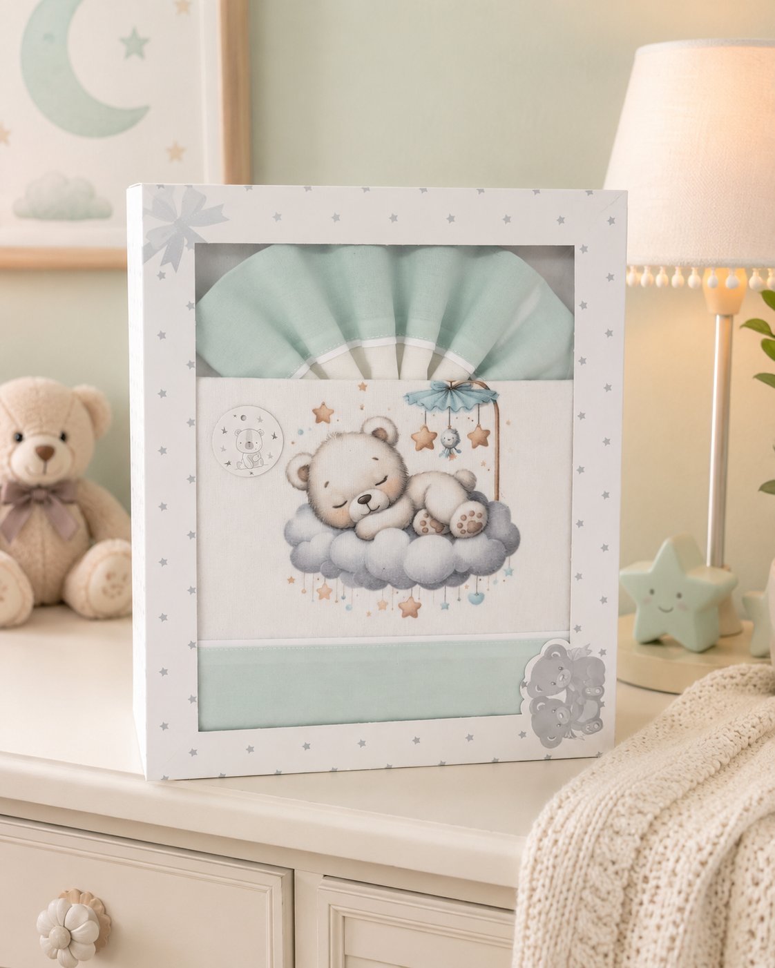 Conjunto de roupa de bebé azul e branco com estampa de urso sobre nuvem na caixa em móvel com lâmpada, urso de peluche e manta