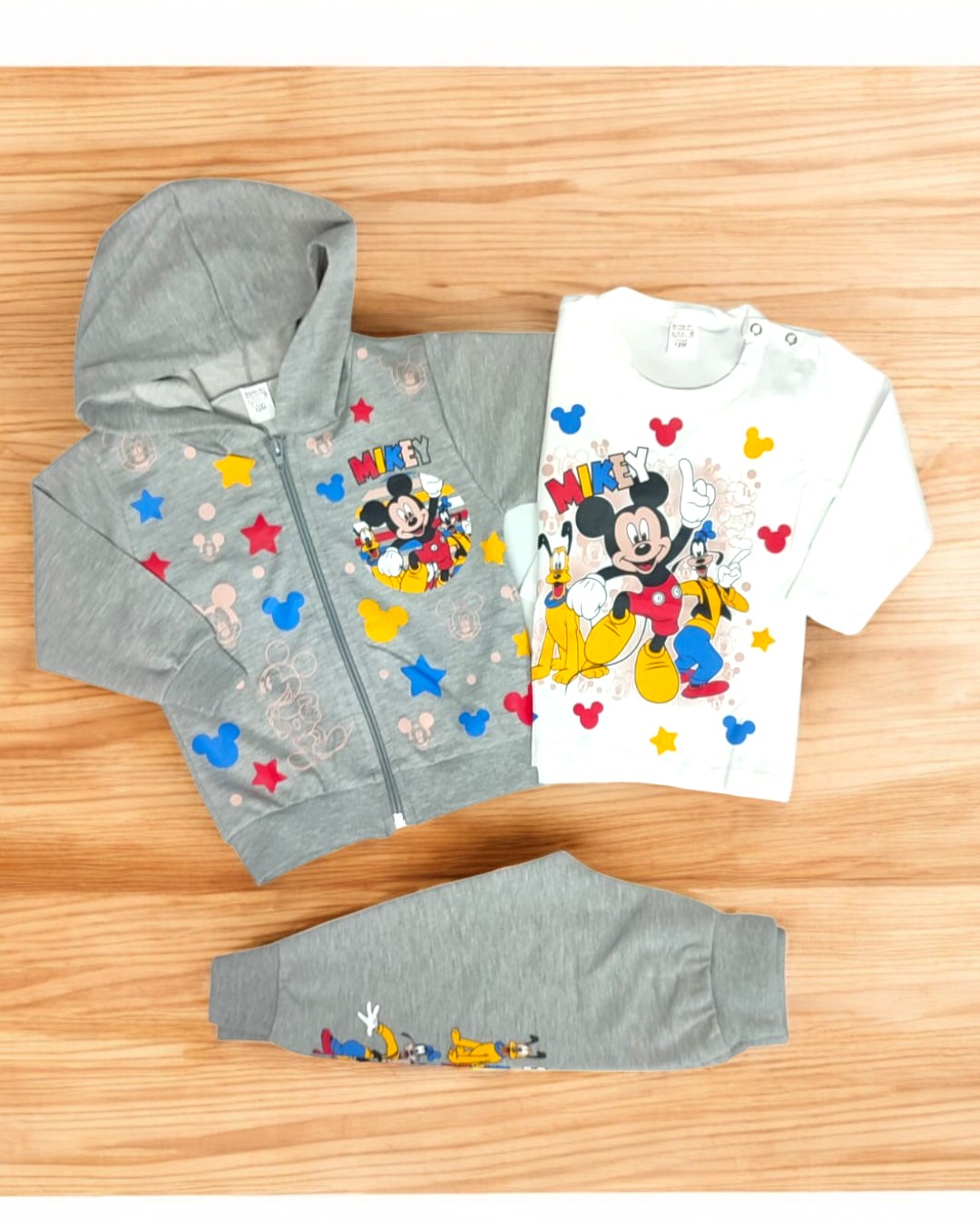 Conjunto infantil com casaco cinza, t-shirt branca e calças cinza com estampados do Mickey Mouse e estrelas coloridas