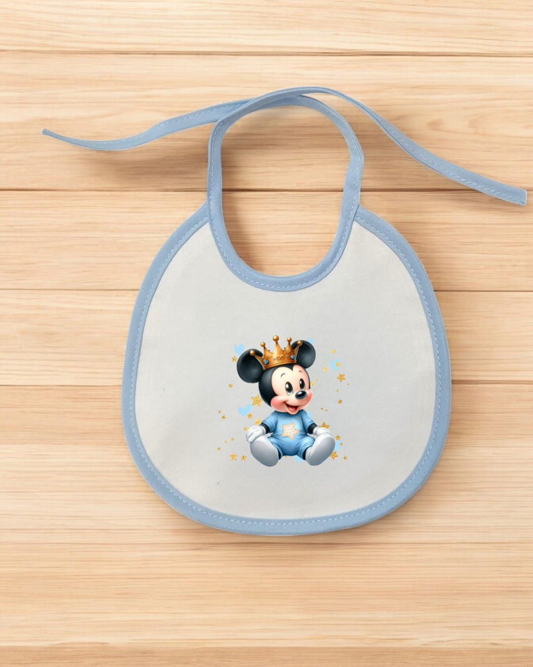 Babete de bebé branco com contorno azul e estampa de Mickey bebé com coroa dourada.