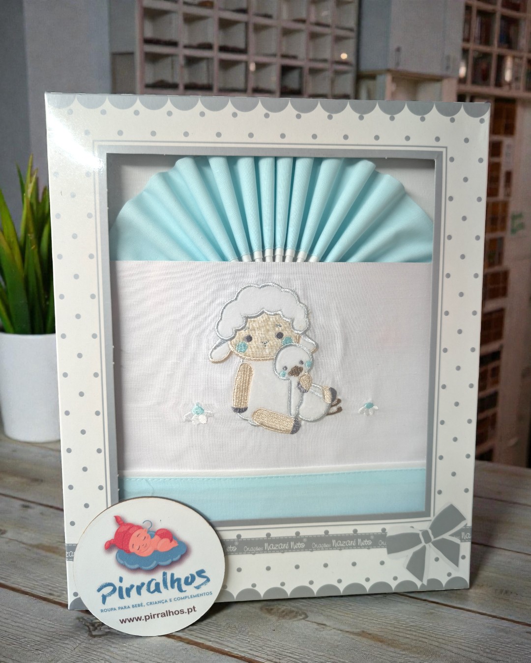 Conjunto de roupa de bebé azul e branco com bordado de carneiro e patinho em embalagem decorada com bolinhas cinzentas