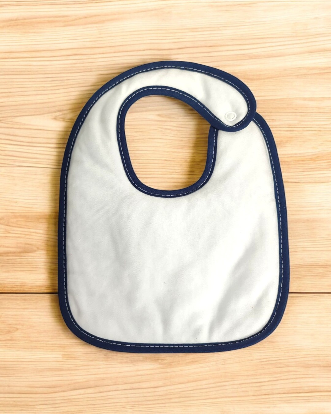 Babete branco com bordas azuis em fundo de madeira clara