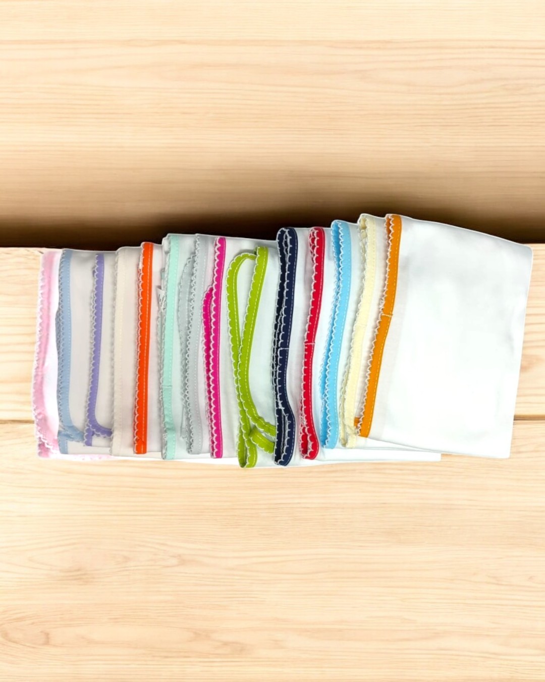 Lenços brancos com bordas coloridas variados sobre madeira