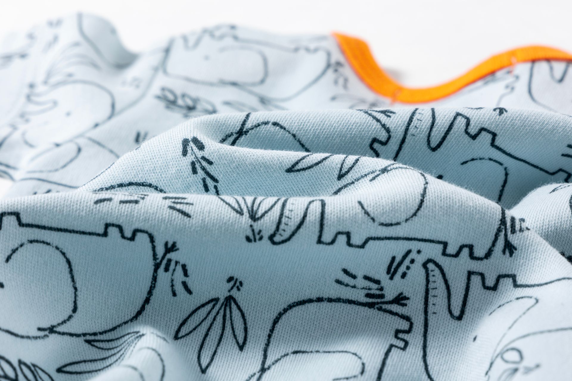 Tecido azul claro com padrão preto de animais e plantas e borda laranja
