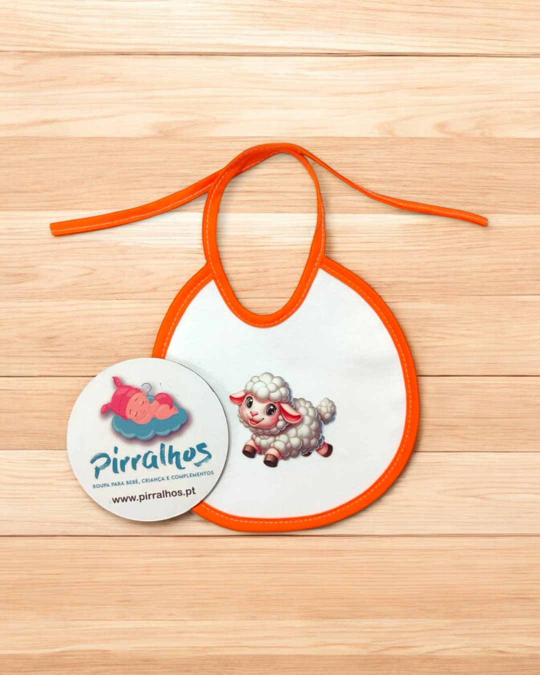 Babete branco com bordas laranja e estampa de ovelha, etiqueta da marca Pirralhos