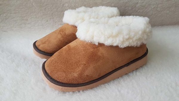 Pantufas caramelo com pelúcia branca e sola bege sobre fundo felpudo branco