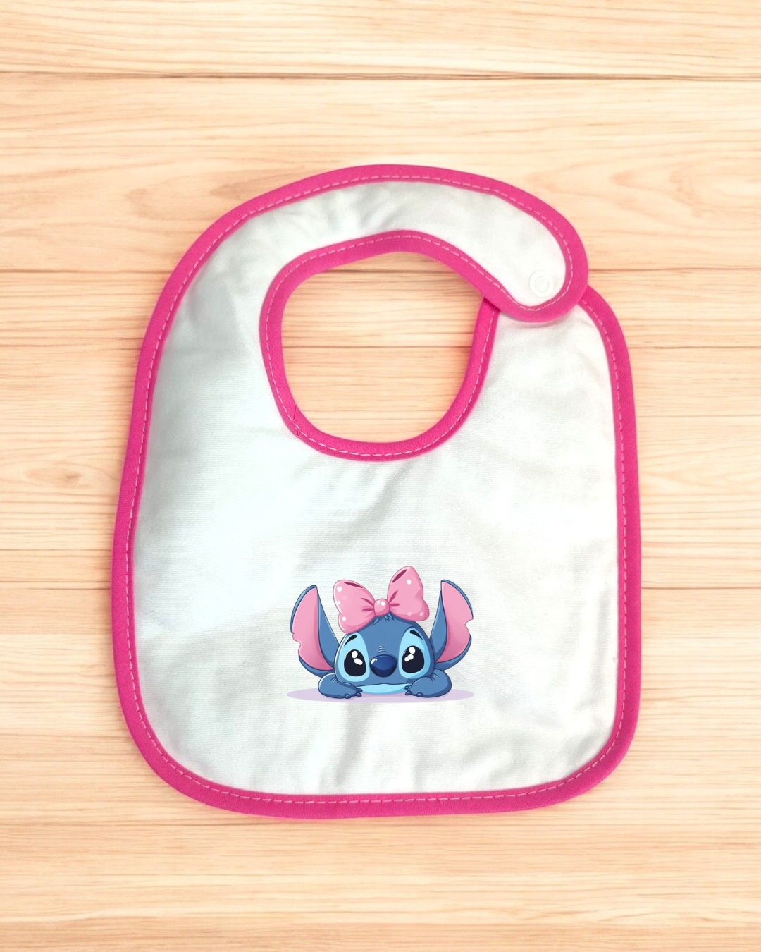 Babete branco com borda rosa e personagem azul com laço cor-de-rosa