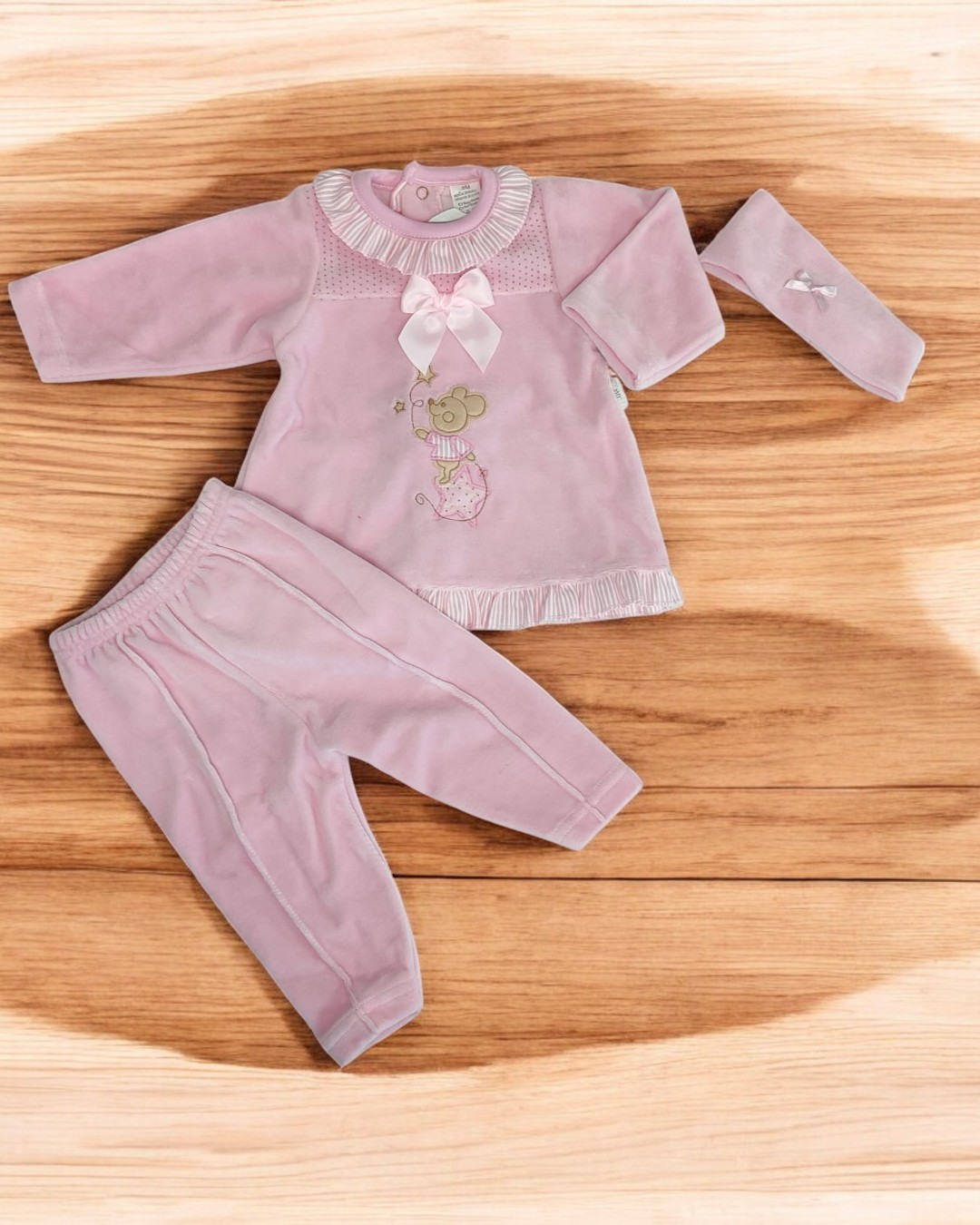 Conjunto de roupa infantil rosa em veludo com camisola, calças e faixa para cabeça sobre madeira clara