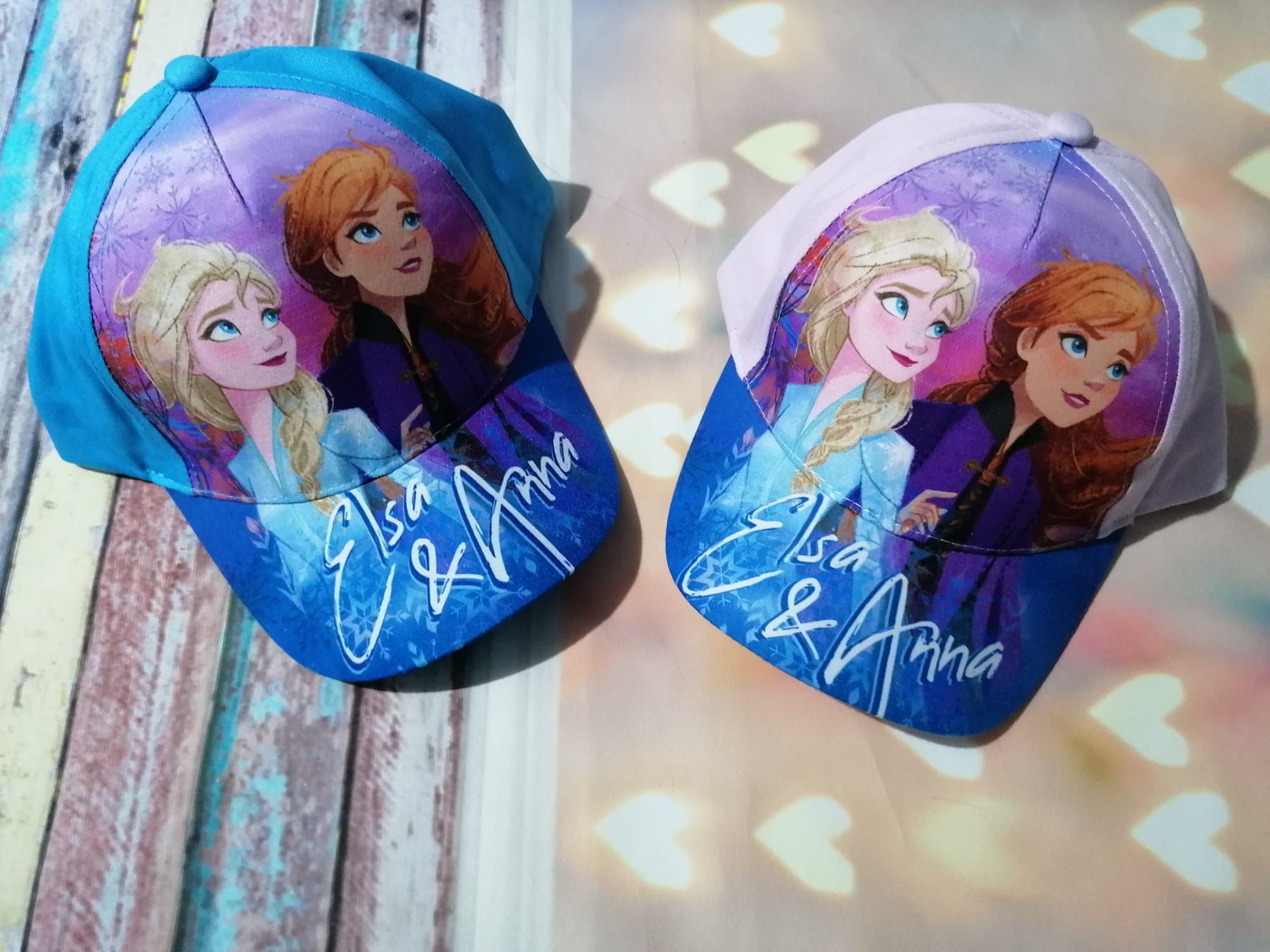 Dois bonés infantis com imagens das personagens Elsa e Anna do Frozen