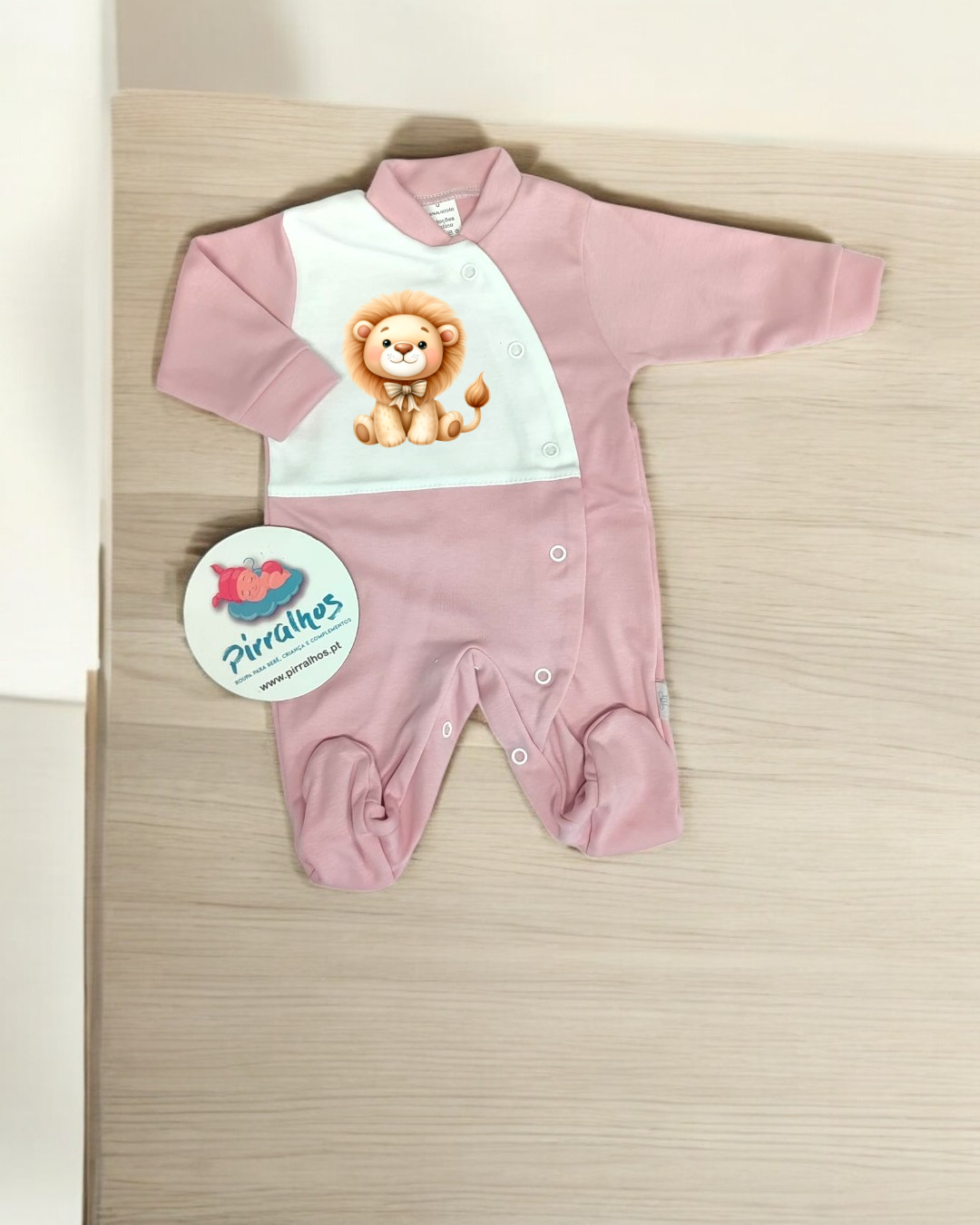 Macacão de bebé rosa e branco com leão desenhado e etiqueta Pirrilhos