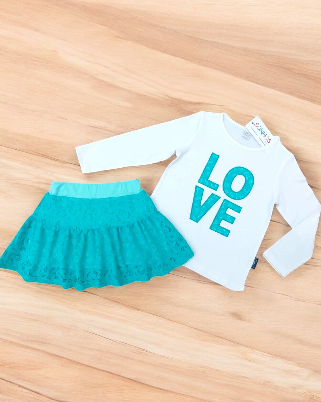 Conjunto infantil t-shirt branca manga comprida com palavra LOVE azul-turquesa e saia azul-turquesa com padrão em relevo