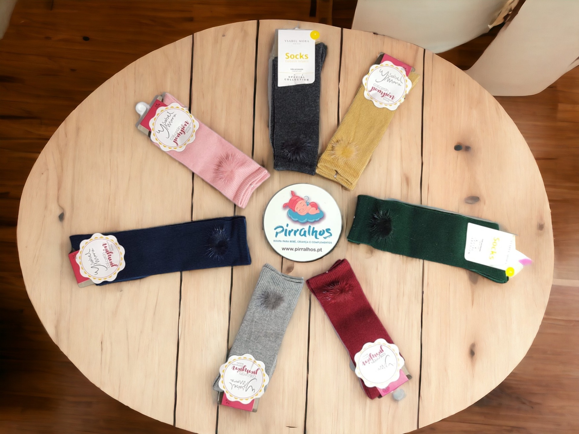 Sete pares de meias coloridas em círculo sobre mesa redonda de madeira clara