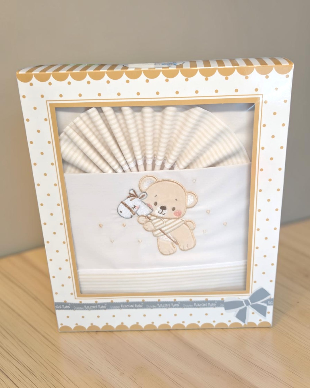 Roupa de bebé bege e branca com ursinho bordado em caixa decorativa