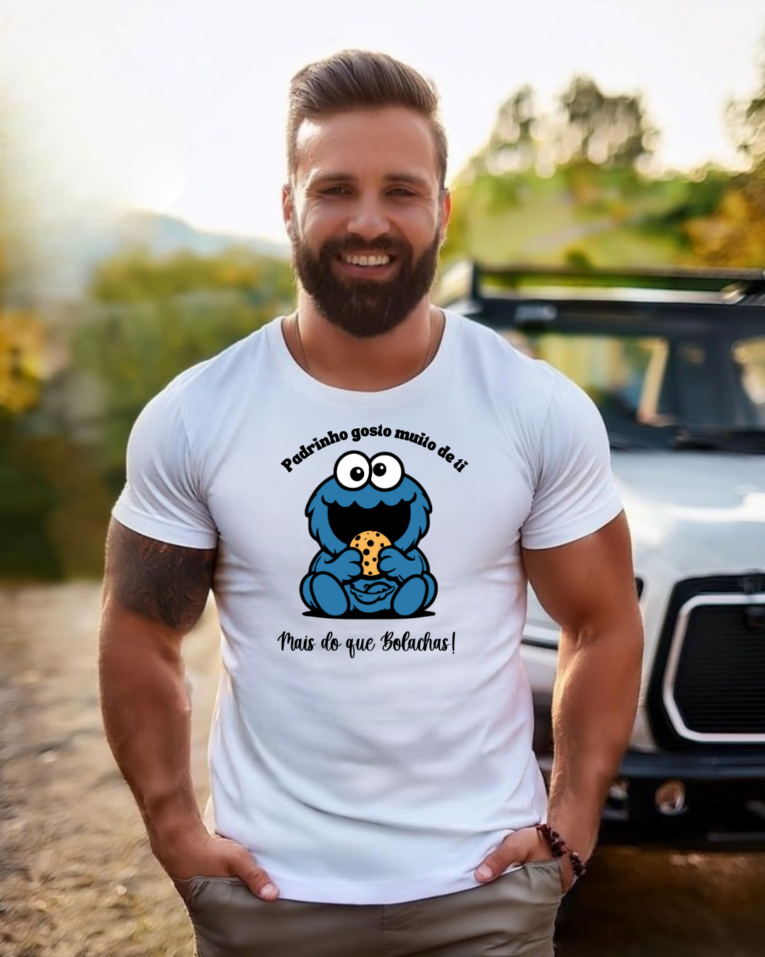 Homem com t-shirt branca e estampa do Monstro das Bolachas, texto em português, ao ar livre com carro ao fundo