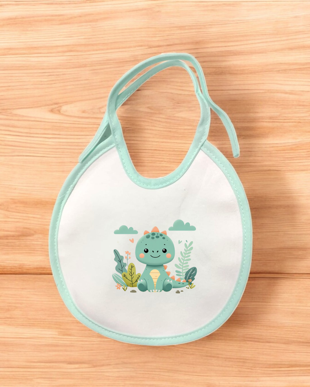 Babete branco com borda azul claro e desenho de dinossauro verde