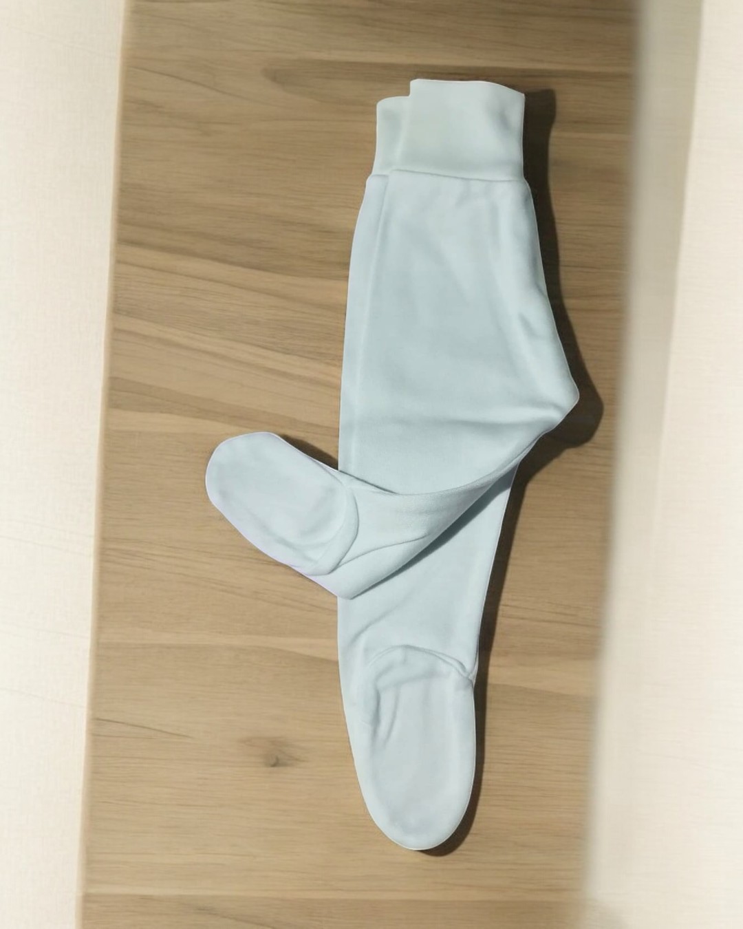 Meia-calça branca sobre madeira clara