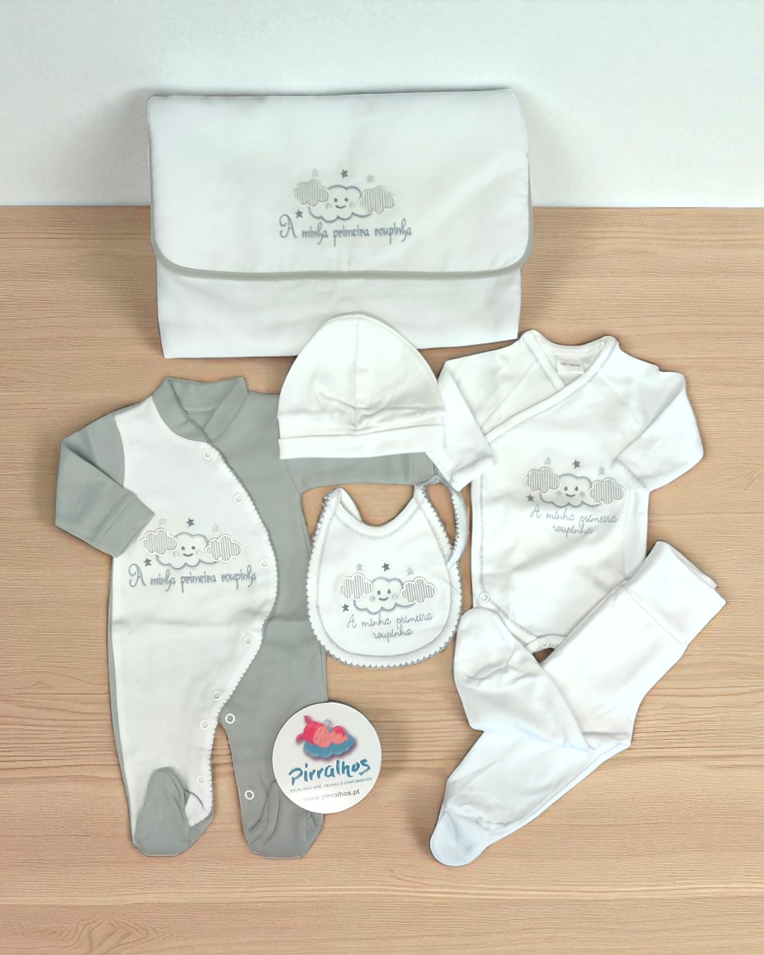 Conjunto para bebé em cinza e branco com elefante e texto, sobre mesa de madeira clara
