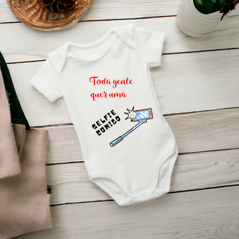 Body branco para bebé com texto e desenho colorido sobre superfície de madeira clara