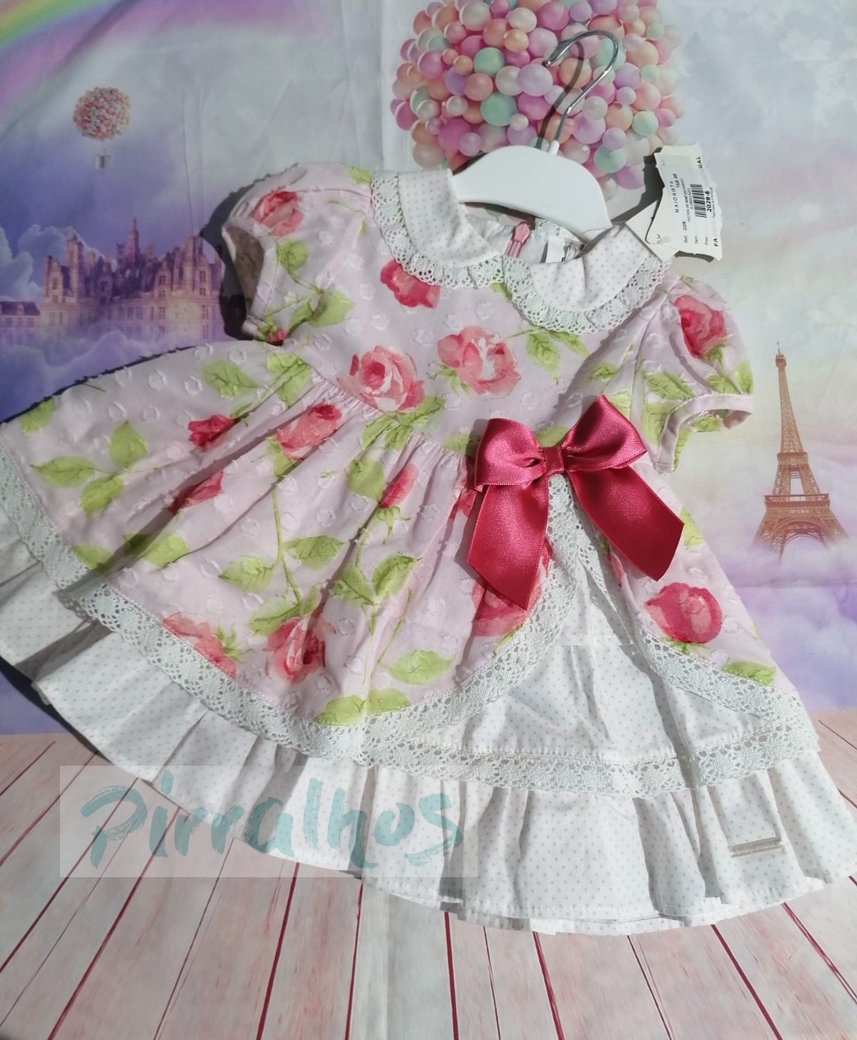 Vestido infantil rosa claro com padrão de rosas e laço rosa