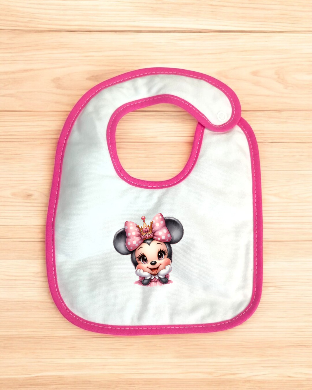 Babete para bebé com desenho da Minnie Mouse e borde rosa em fundo de madeira