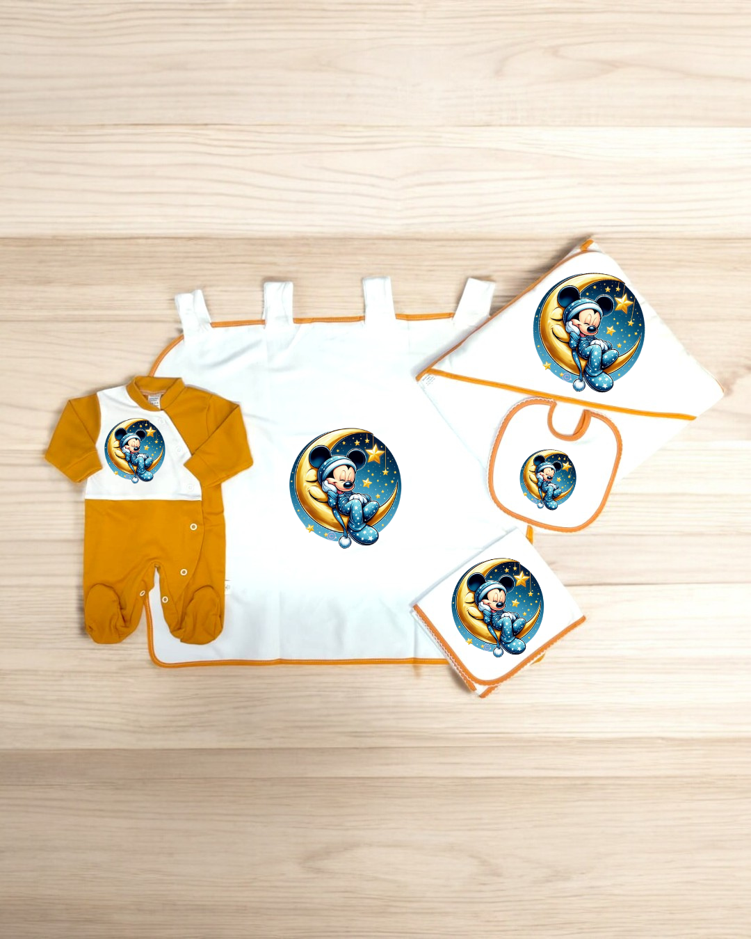Conjunto de roupa de bebé com macacão amarelo e branco e toalhas com bordas laranja e personagem de desenho animado mágico