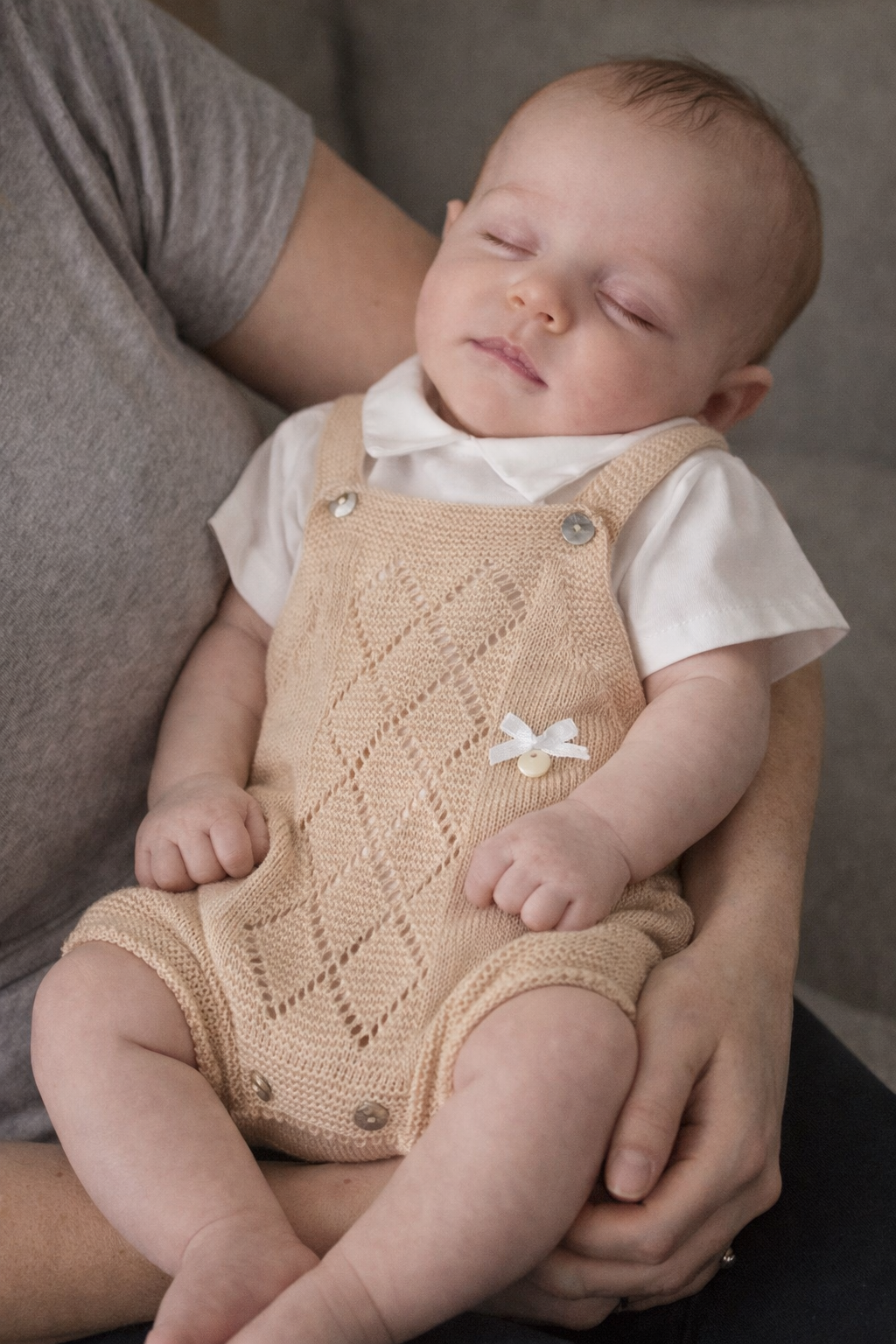 Bebé adormecido com fato de malha bege e camisa branca