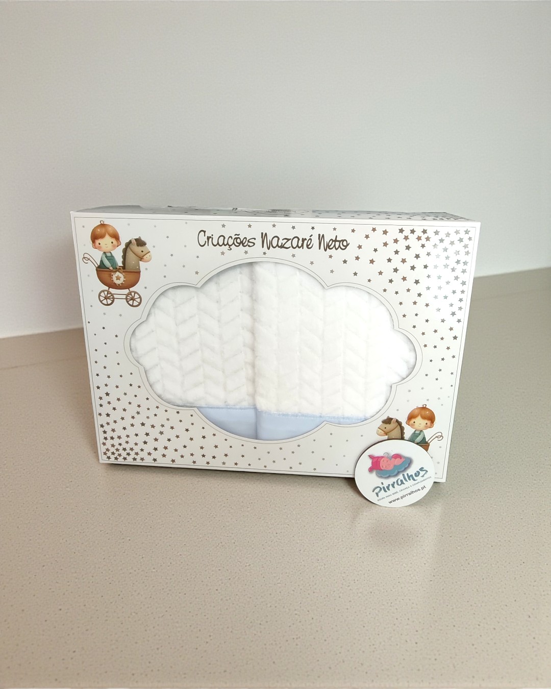 Embalagem branca decorada com estrelas douradas e ilustrações de criança num carrinho com cavalo