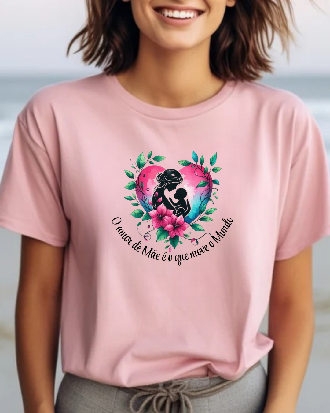 T-shirt rosa com estampa de mãe e filho rodeados de flores e texto em português.